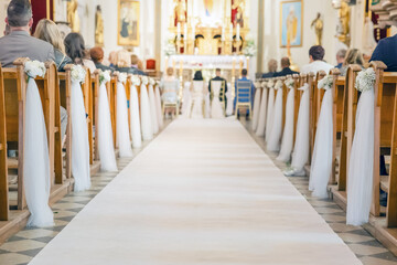 White tulle ribbon tied to wooden pew as wedding church decoration