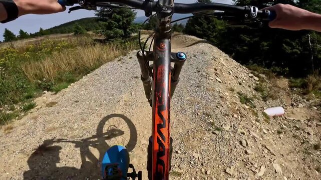 POV: Dynamic first-person ride on a gravel surface with sharp turns. Capturing the thrill and technical challenges of MTB downhill.