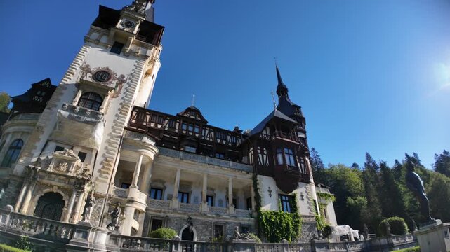 Peles Castle, stunning Neo-Renaissance royal palace, stands against a clear blue sky, showcasing its elaborate architecture, stone balustrades, and vibrant green climbing ivy in Transylvania, Romania