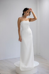 Fototapeta premium Stylish bride in strapless white gown posing gracefully, elegant and modern bridal portrait