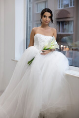 Bride in glamorous white ball gown with sparkling bodice holding calla lily bouquet