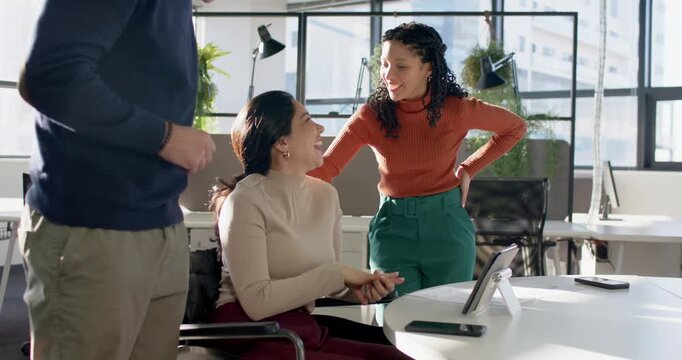 Phone pinging urging diverse coworkers leaning on wheelchair laughing discussing tablet at desk