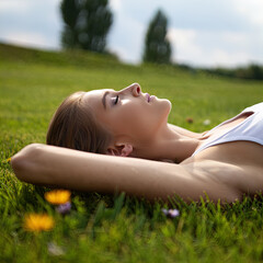 A young woman relaxes and breathes in the fresh air at sunset, unwinding against a beautiful backdrop.