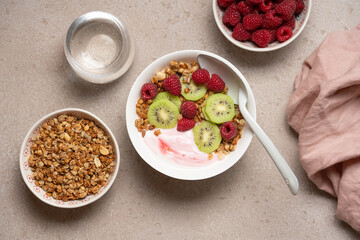 Top View of Raspberry Yogurt in White Bowl with Fresh Kiwi Topping and Ripe Raspberries on Beige Background, Healthy Dessert and Breakfast Concept