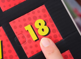 Woman finger pointing at the number 18 on an advent calendar.