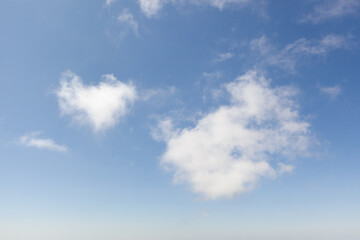 Cloud shapes in a clear blue sky over a serene landscape during a sunny afternoon
