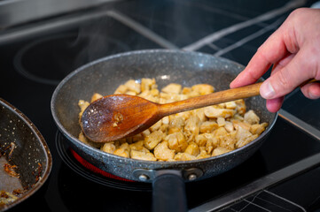 Frying Meat Pieces in Pan, wooden spoon for mixing,