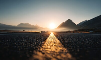 Asphalt road leading to sunrise over mountains