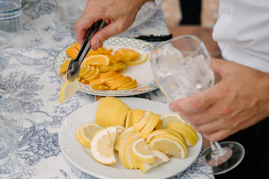 Primer plano de persona tomando una rodaja de limon con una pinza paar ponerlo en un vaso o copa de bebida o refresco