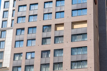 Modern, multi-storied building with a mix of brickwork and glass panels Curtained windows, gray concrete, black metal frames, red bricks, soft shadows, urban detail, cityscape, no contextual signs