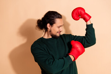 Young man posing with red boxing gloves showcasing strength and confidence against a beige background