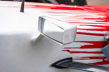 Close-up view of a damaged Formula 1 car with red and white bodywork, displayed from above Engine bay visible with complex components, shadows cast by lighting Splattered paint suggests collision o
