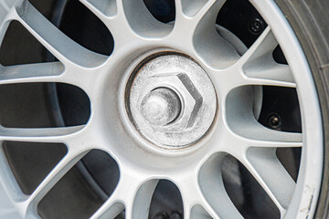 Close-up view of a silver Formula 1 wheel with multiple spoke patterns, dirty from outdoor use or driving Lug nut assembly visible at the hub Neutral background Even lighting, suggesting indoor or