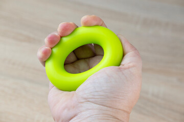 Green rubber hand grip tool used for developing hand strength and rehabilitation after injuries or paralysis