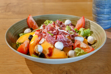 Salade fraîche de melon, jambon cru, mozzarella et tomates, plat estival gourmand