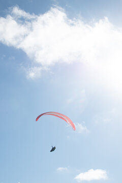 Beautiful day for paragliding over a scenic landscape with clear blue skies and fluffy clouds