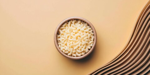 A wooden bowl filled with uncooked elbow macaroni pasta sits on a beige background with textured fabric