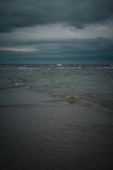 Dramatic coastal scene with dark clouds over calm waters at sunset