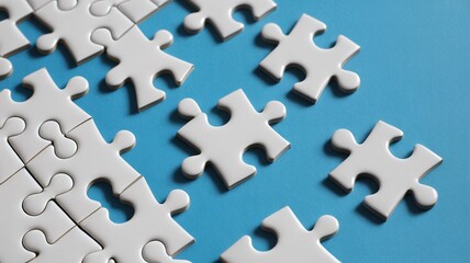 Obraz premium White puzzle pieces scattered on blue background, concept of solution