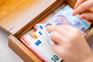 Little Child taking euro banknotes from wooden box, removing cash, innocent look, concept childhood curiosity and money temptation, early lessons about value, temptation, and consequences of actions