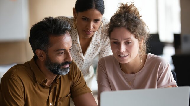 professional indian teacher executive or mentor helping latin student new employee teaching intern explaining online job using laptop computer talking having teamwork discussion in office no logos no