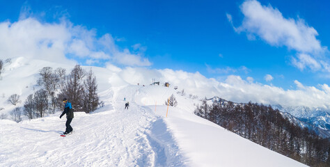 Panoramic view of the ski resort top showing the contrast between a tracked slope and fresh powder snow (Maiko, Minamiuonuma, Niigata, Japan)