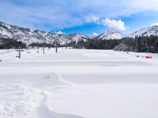 A kids' park set in deep fresh snow with a view of chairlifts and the Mount Iiji (Maiko, Minamiuonuma, Niigata, Japan)