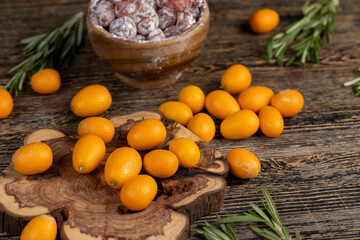 fresh and dried kumquat fruits on the table, fresh orange kumquats and dehydrated dried kumquats sprinkled with powdered sugar