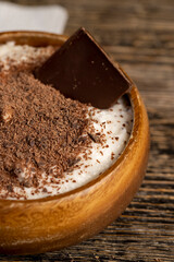 sweet yogurt in a wooden bowl with crumbs, chocolate pieces in milk yogurt, sweet dessert with chocolate flavor