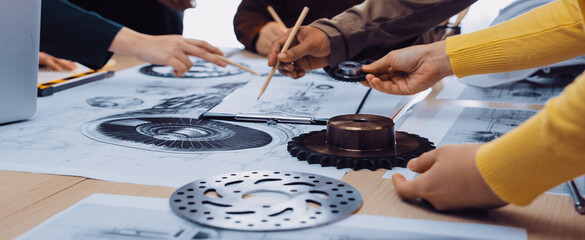 A dynamic group of professionals engages in a vibrant brainstorming session, collaborating around design sketches and mechanical components, fostering creativity and innovation. SACTR