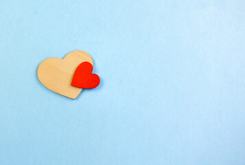 Two hearts made of wood on a blue background with space for a copy, a red and a yellow heart. The concept of family, intimacy, friendship. Two hearts, small and large, are joined together. Blue Paper