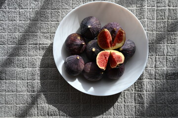 A selection of fresh, ripe purple figs on a clean white plate. High-quality natural product for eco-conscious food brands, product packaging, and healthy ingredient promotion.
