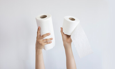 Woman hands holding toilet napkin and paper towel isolated on gray background. Close-up roll of napkin. 