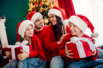 Happy family sharing gifts near a beautifully decorated Christmas tree, cherishing togetherness in a festive holiday atmosphere