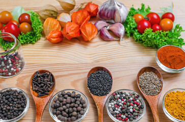 Spices and vegetables arranged on wooden background. Small bowls and wooden spoons with ingredients.