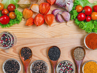Spices and vegetables arranged on wooden background. Small bowls and wooden spoons with ingredients.