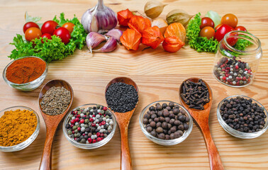 Spices and vegetables arranged on wooden background. Small bowls and wooden spoons with ingredients.