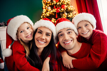 Joyful family celebrating Christmas together at home in cozy red sweaters near beautifully...