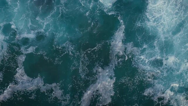 Rolling swell breaking into froth, aerial view. Sea surface detail useful as background