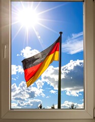 German flag waving in a sunny sky through a window