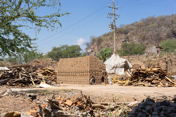 Kiln for firing of handmade bricks, pile of raw bricks drying in the sun, artesanal clay brick production. Guadalajara, Jalisco, March 29 2024.