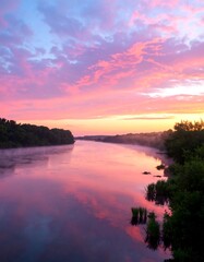 Serene river at sunrise.  Tranquil colors of sunrise paint the sky, reflecting on a still river,  bordered by lush greenery and gentle mist