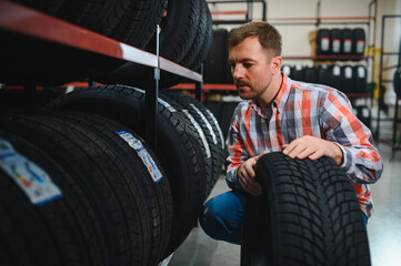 Fototapeta premium Tire repair service. A man chooses new tires for his car.