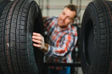 Portrait young man customer examining brand and product characteristics while buying new tires in auto department of dealership. Male client choosing car accessories shopping mall © Serhii