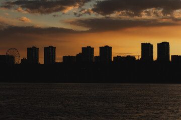 Sunset over city skyline with dark silhouettes and vibrant orange sky