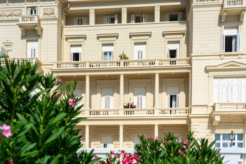 Elegant neoclassical building facade with balconies, shutters, and blooming flowers