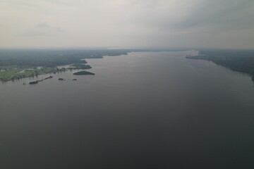 Overview of a wide river surrounded by lush greenery under a cloudy sky