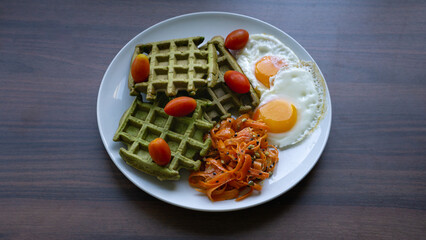 Fried eggs with waffles cherry tomatoes and carrot salad