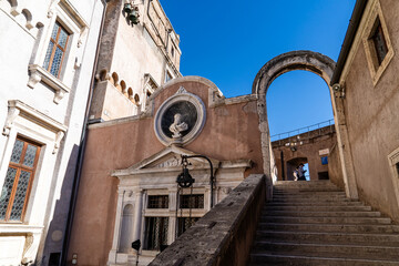 Historic arch and stairs leading up to Castel Sant'Angelo in Rome on a sunny day. Renaissance architecture and clear blue sky.