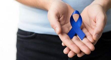 Fototapeta premium Close up of hands holding a blue ribbon symbol of awareness for colon cancer and prostate cancer awareness month awareness day